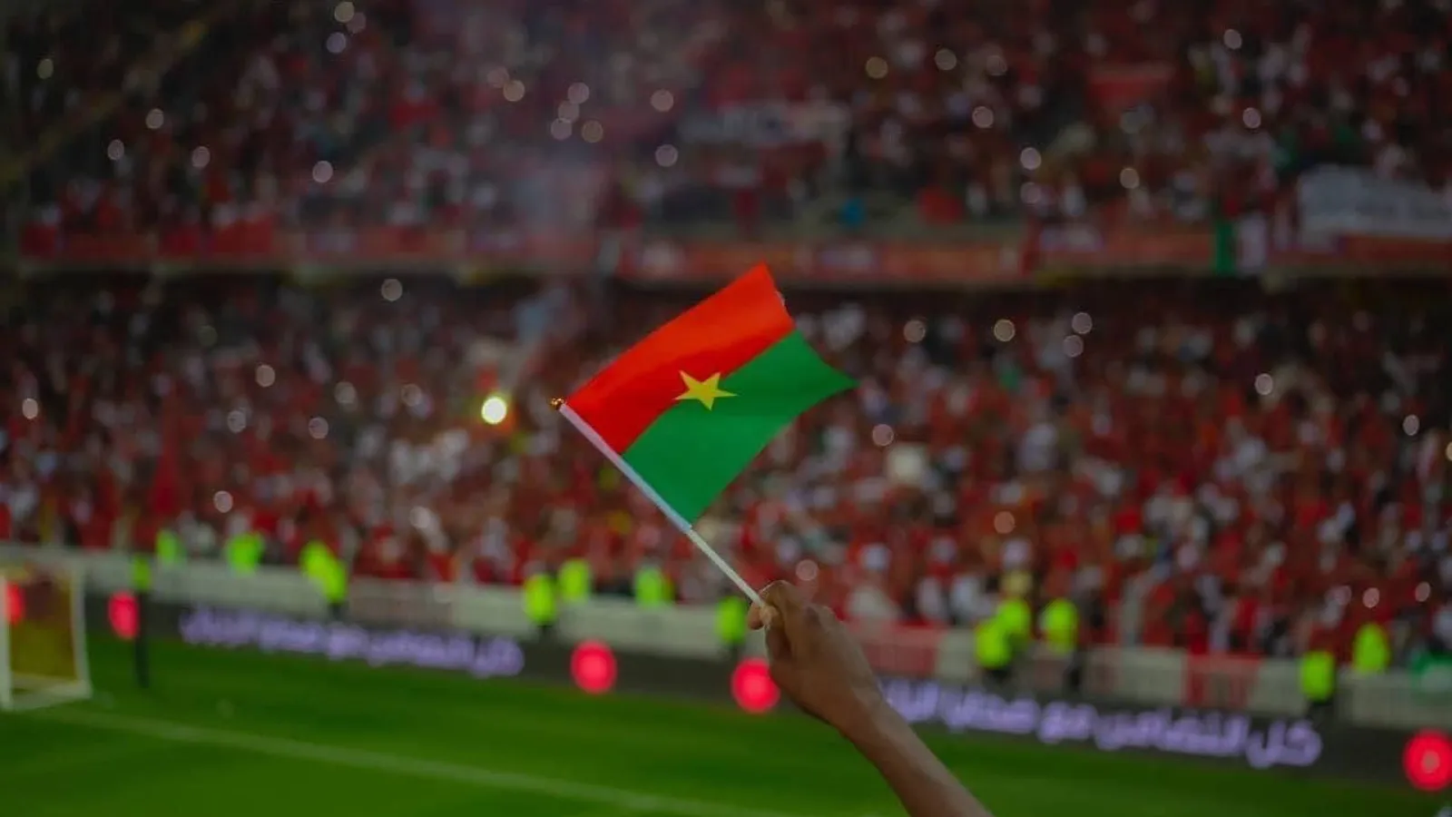 Supporter agitant le drapeau du Burkina Faso dans un stade
